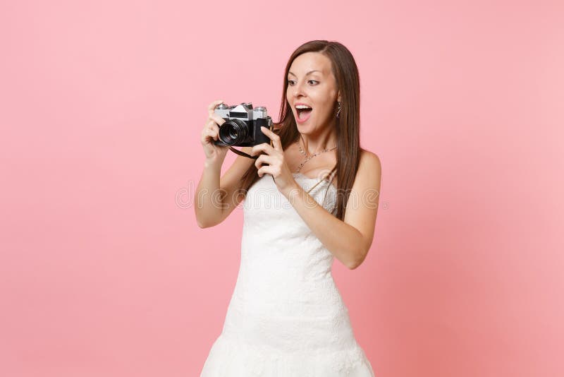 Mulher surpreendida da noiva no vestido de casamento que toma imagens na câmera retro da foto do vintage que escolhe o pessoal, f imagem de stock Mulher surpreendida da noiva no vestido de casamento que toma imagens na câmera retro da foto do vintage que escolhe o pessoal, f imagem de stock