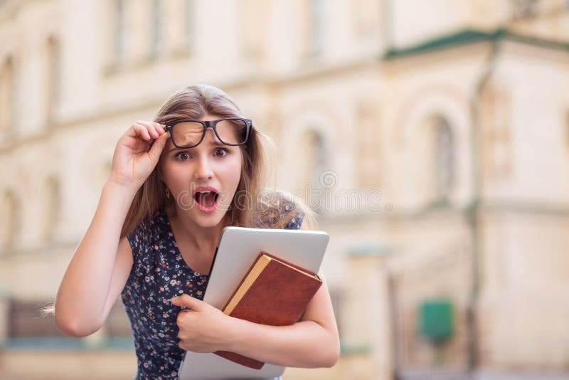 Mulher surpreendida do estudante que mant?m vidros com livros e PC foto de stock Mulher surpreendida do estudante que mant?m vidros com livros e PC foto de stock