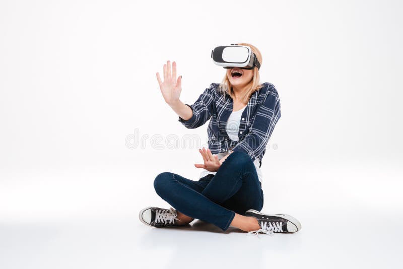 Mulher surpreendida que senta-se no assoalho que veste vidros de VR imagem de stock royalty free Mulher surpreendida que senta-se no assoalho que veste vidros de VR imagem de stock royalty free