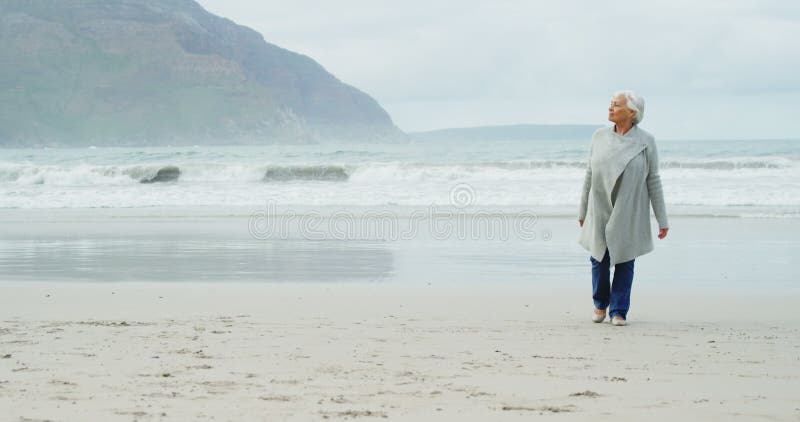 Mulher sênior que anda na praia