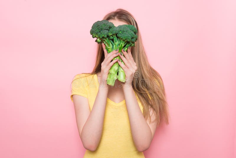 A mulher tem o divertimento que guarda o vegetal verde orgânico sem glúten Conceito saudável do alimento da nutrição foto de stock royalty free A mulher tem o divertimento que guarda o vegetal verde orgânico sem glúten Conceito saudável do alimento da nutrição foto de stock royalty free