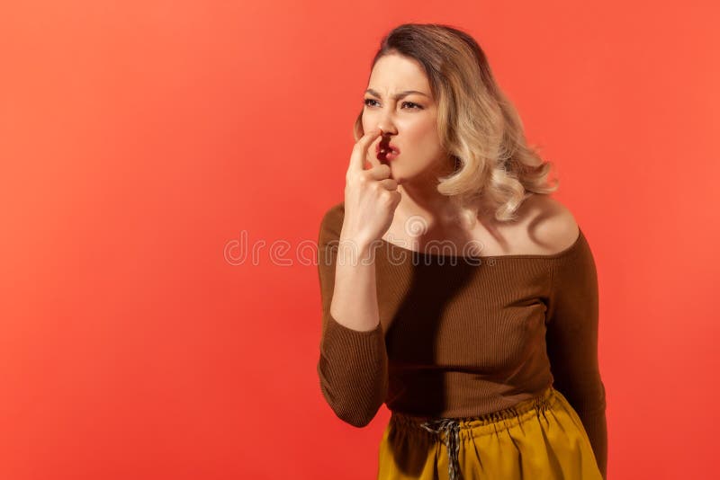 This is lie! Portrait of angry woman with blonde hair touching nose, showing liar gesture, expressing distrust of false suggestion, deception. Indoor studio shot isolated on red background. This is lie! Portrait of angry woman with blonde hair touching nose, showing liar gesture, expressing distrust of false suggestion, deception. Indoor studio shot isolated on red background