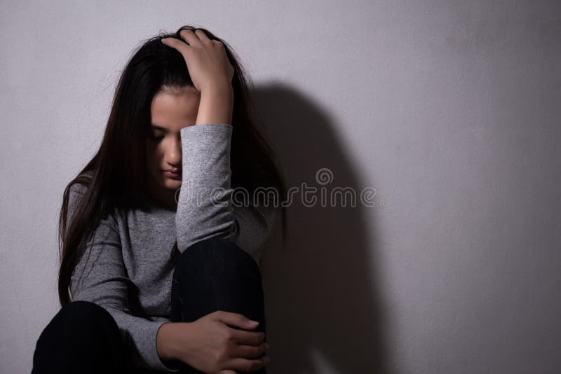 A mulher com depressão abraça o joelho e chora. a mulher triste