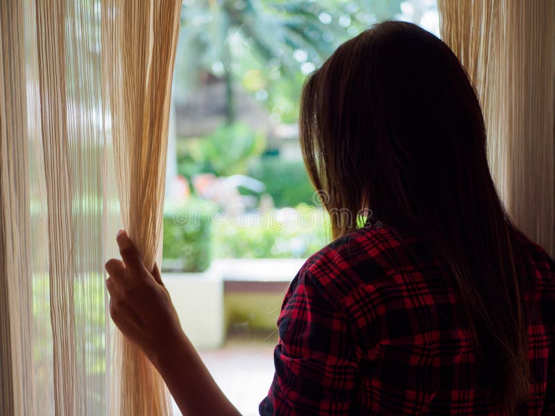 A Opinião Traseira Uma Jovem Mulher Que Guarda As Cortinas Abre Para Olhar  Em Casa Fora De Uma Grande Janela Clara Foto de Stock - Imagem de vidro,  interior: 92278598