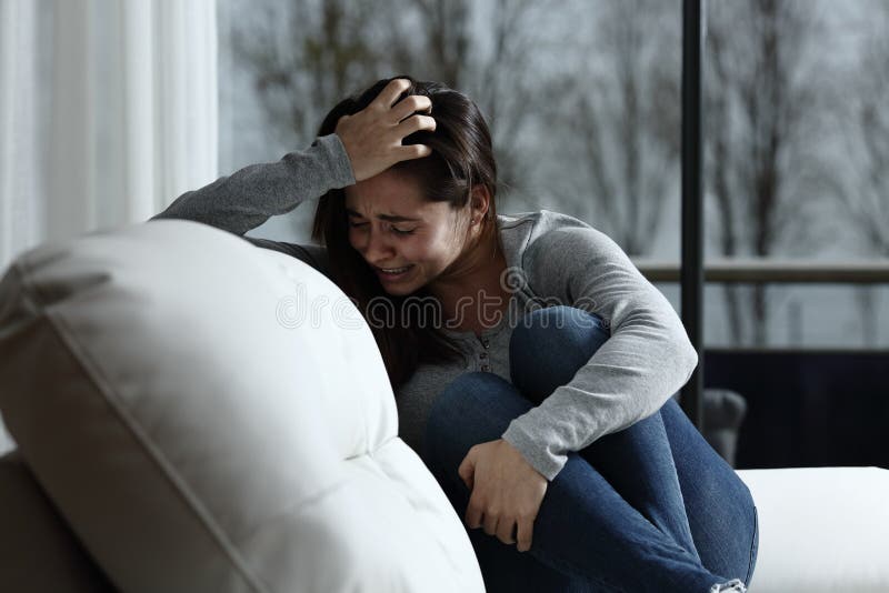 Sad woman complaining and crying sitting on a couch in the living room at home. Sad woman complaining and crying sitting on a couch in the living room at home