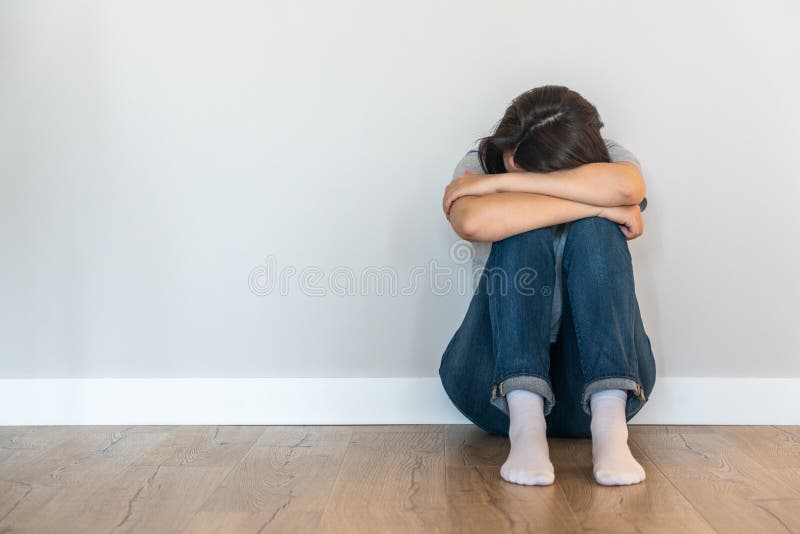 Menina triste sentada sozinha no chão