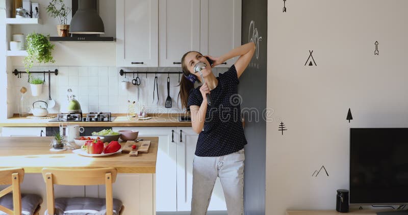 Mulher usa fones de ouvido segurando uma escada como microfone dançando música