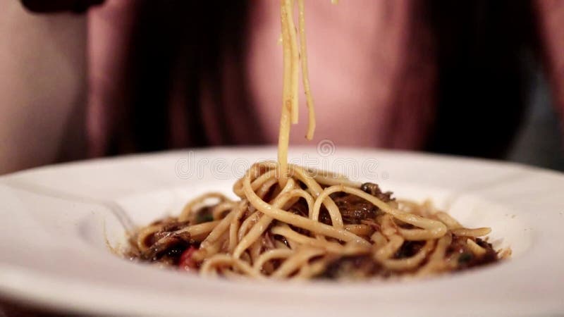 Mulher usando garfo e colher para comer molho de carne de esparguete no restaurante. foco seletivo. tiro de closet