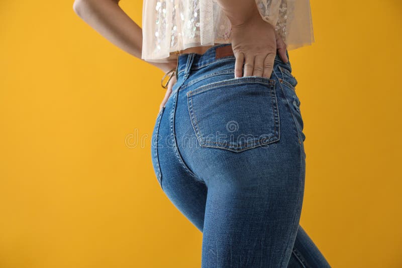 Mulher de calças de ganga em fundo amarelo, close-up fotografia de stock