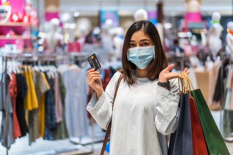 Mulher usando máscara médica e segurando cartão de crédito no shopping center para prevenção da pandemia de coronavírus19. novo