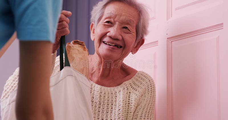 Mulher voluntária entrega comida a mulher idosa pobre em casa.