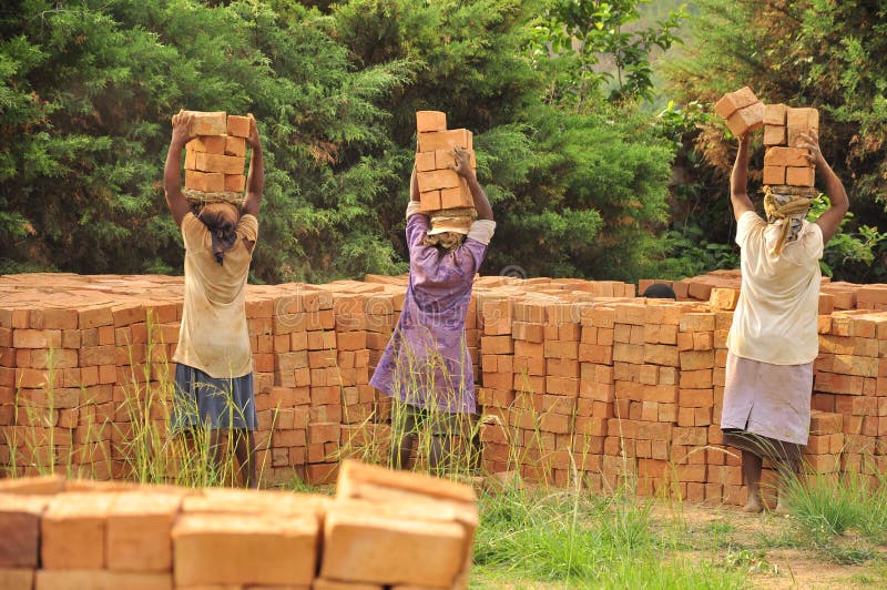 Mulheres africanas em tijolos levando do trabalho