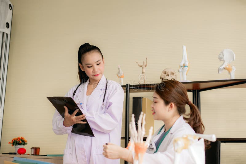 Mulheres asi?ticas educa??o e utiliza??o da estudante de Medicina do modelo de esqueleto da m?o no hospital junto imagens de stock royalty free Mulheres asi?ticas educa??o e utiliza??o da estudante de Medicina do modelo de esqueleto da m?o no hospital junto imagens de stock royalty free