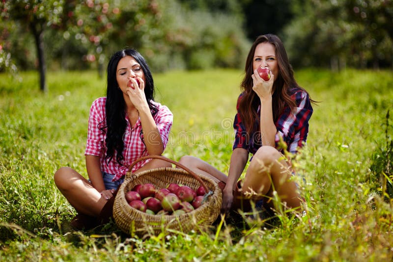 Mulheres bonitas que tomam uma mordida de uma maçã imagem de stock royalty free Mulheres bonitas que tomam uma mordida de uma maçã imagem de stock royalty free