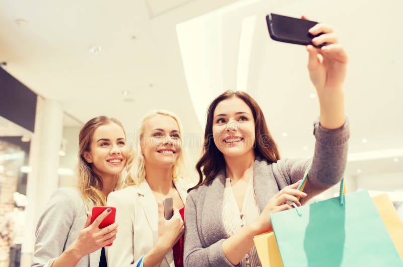 Mulheres com smartphones que compram e que tomam o selfie fotografia de stock royalty free Mulheres com smartphones que compram e que tomam o selfie fotografia de stock royalty free