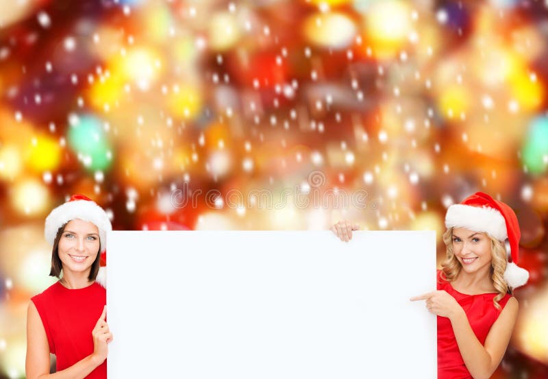 Mulheres em chapéus do ajudante de Santa com placa branca vazia fotos de stock Mulheres em chapéus do ajudante de Santa com placa branca vazia fotos de stock
