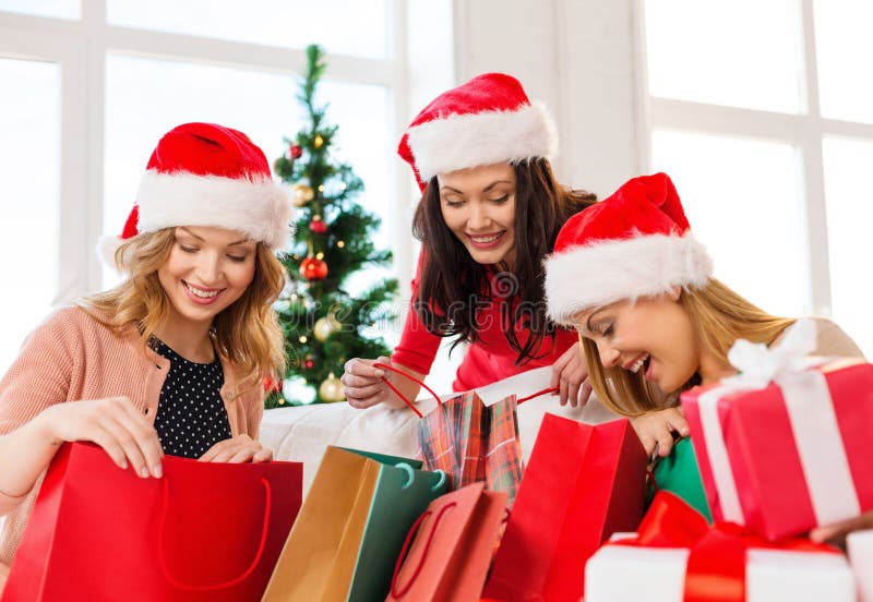 Mulheres em chapéus do ajudante de Santa com sacos de compras foto de stock Mulheres em chapéus do ajudante de Santa com sacos de compras foto de stock