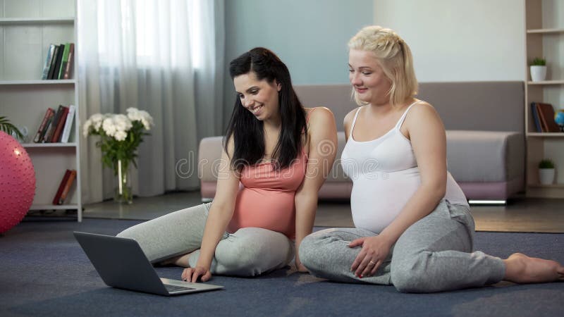 Mulheres gravidas que veem os Web site no portátil, compra em linha para as mamãs futuras foto de stock royalty free Mulheres gravidas que veem os Web site no portátil, compra em linha para as mamãs futuras foto de stock royalty free