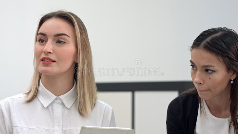 Mulheres ocupadas do escritório no escritório que toma o telefonema e que usa a tabuleta foto de stock Mulheres ocupadas do escritório no escritório que toma o telefonema e que usa a tabuleta foto de stock