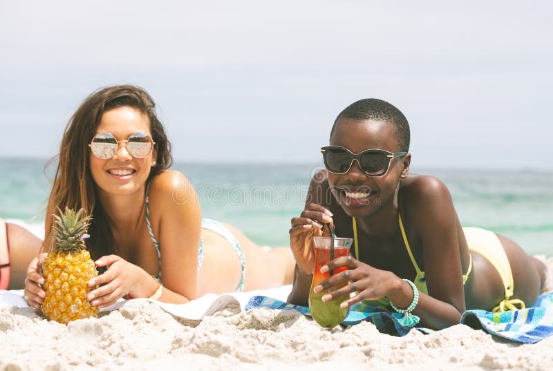 Mulheres que encontram-se na praia ao comer o abacaxi foto de stock Mulheres que encontram-se na praia ao comer o abacaxi foto de stock