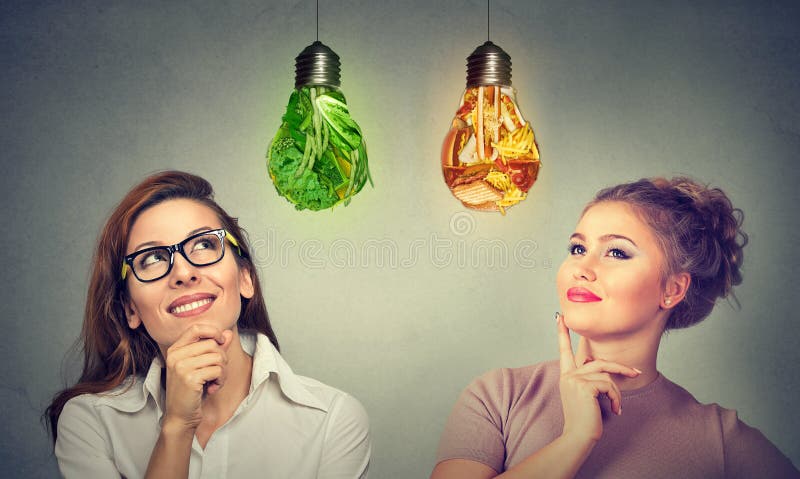 Mulheres que pensam sobre a dieta que olha a ampola da comida lixo dos vegetais fotos de stock Mulheres que pensam sobre a dieta que olha a ampola da comida lixo dos vegetais fotos de stock