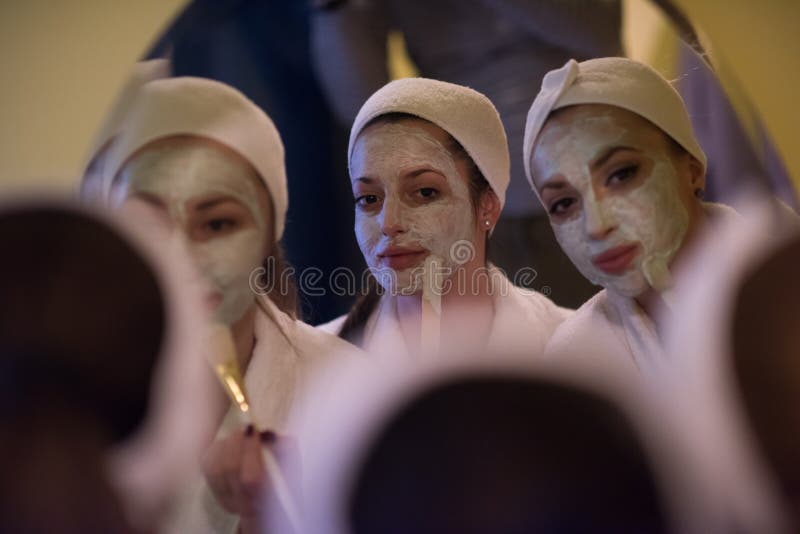 Mulheres que põem máscaraes protetoras no banheiro fotografia de stock Mulheres que põem máscaraes protetoras no banheiro fotografia de stock