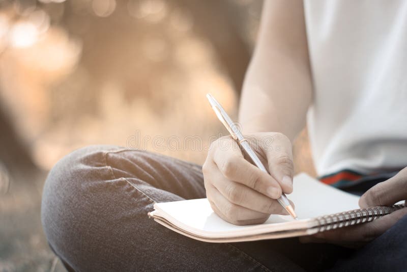 Mulheres que situam e que escrevem a memória no caderno no parque no verão fotos de stock Mulheres que situam e que escrevem a memória no caderno no parque no verão fotos de stock