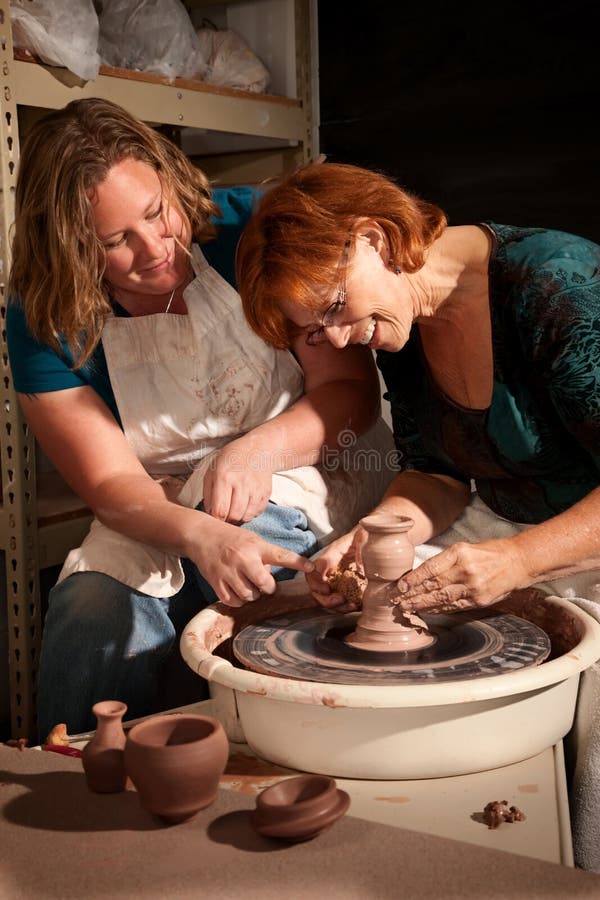 Teacher and student in clay studio working at the wheel. Teacher and student in clay studio working at the wheel