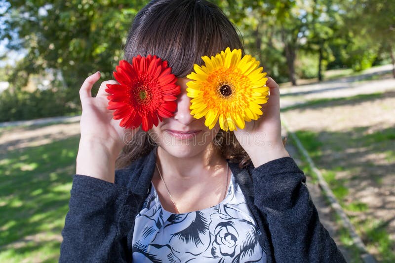 Women having fun hiding her pretty eyes by two flowers. Women having fun hiding her pretty eyes by two flowers.