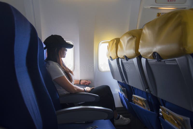 Mulheres que viajam por um avião Mulheres que sentam-se pela janela dos aviões e que olham fora