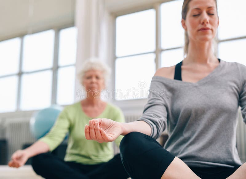 Mulheres relaxado da aptidão que praticam a ioga no gym imagens de stock Mulheres relaxado da aptidão que praticam a ioga no gym imagens de stock