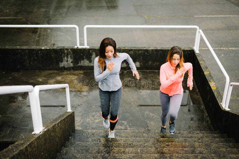 Mulheres urbanas da aptidão que correm e que escalam escadas imagem de stock Mulheres urbanas da aptidão que correm e que escalam escadas imagem de stock