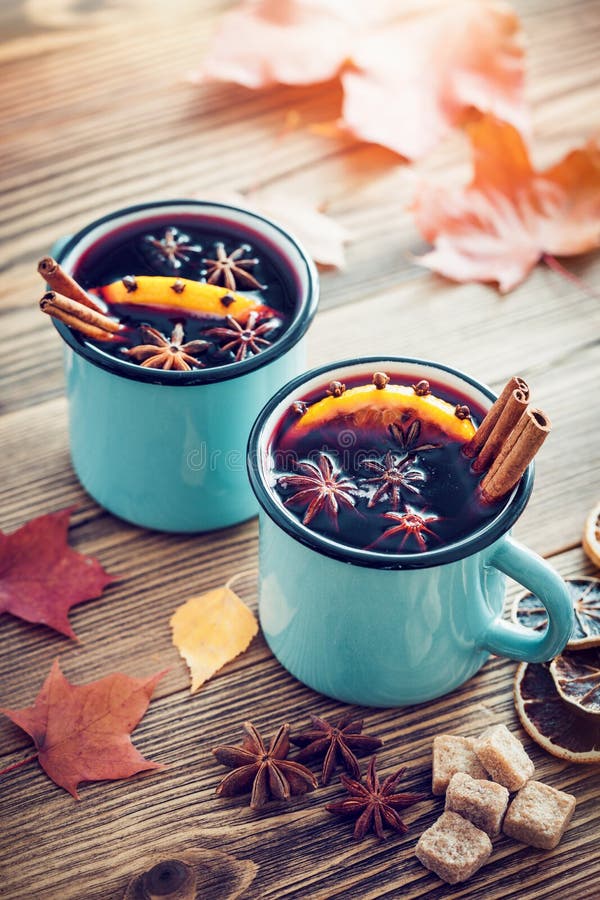 Mulled wine in blue enameled mugs with spices and citrus.