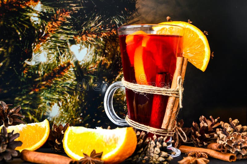 Mulled wine Hot christmas drink with spices on a dark christmas background. Orange slices, cinnamon sticks, christmas cones