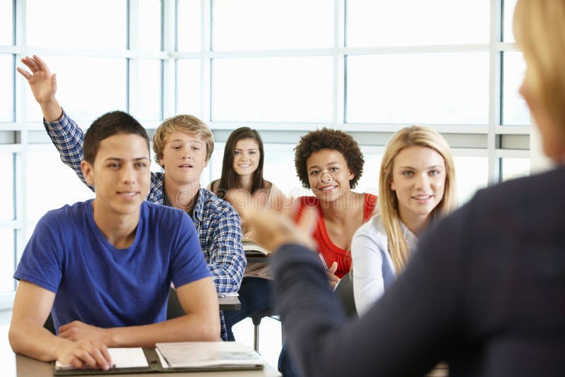 Multi allievi adolescenti razziali nella classe una con la mano su fotografia stock Multi allievi adolescenti razziali nella classe una con la mano su fotografia stock