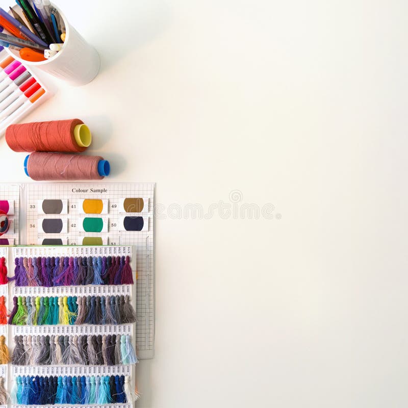 Multi colored magic pens, silk thread color sample catalog, multicolored thread spool and sketching place on a large table. Top stock image