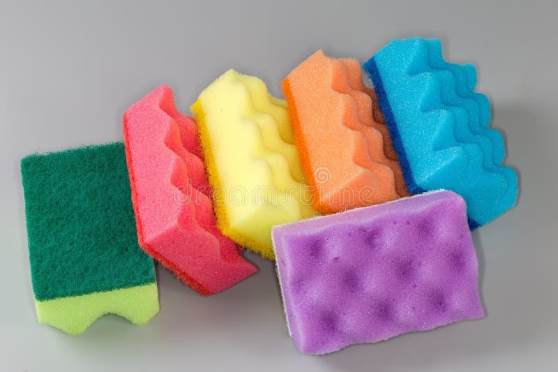 Several multi colored kitchen soft synthetic cleaning sponges with hard urethane abrasive layer on a gray background. Multi colored foam sponges stock images, royalty-free photos and pictures