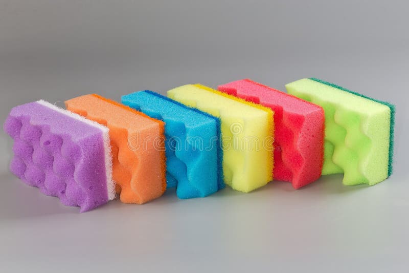 Several multi colored kitchen soft synthetic cleaning sponges with hard urethane abrasive layer on a gray background. Multi colored foam sponges stock images, royalty-free photos and pictures