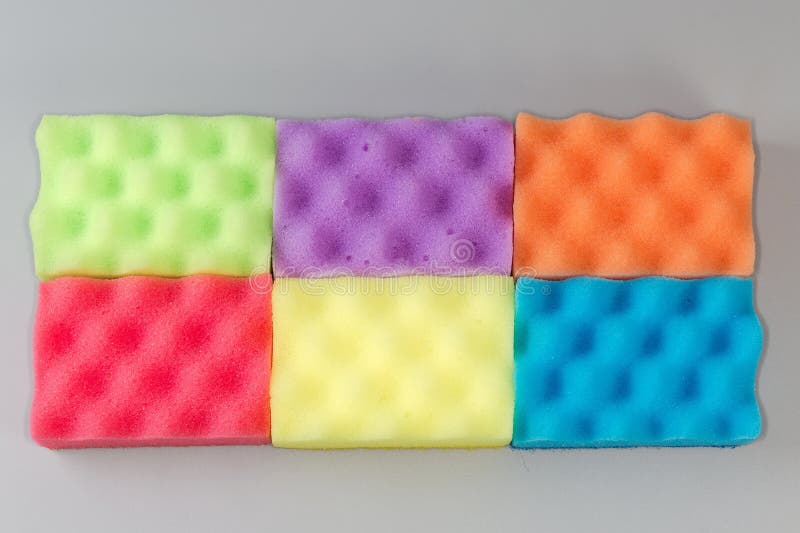 Several multi colored kitchen soft synthetic cleaning sponges laid out on a gray surface. Multi colored foam sponges stock images, royalty-free photos and pictures