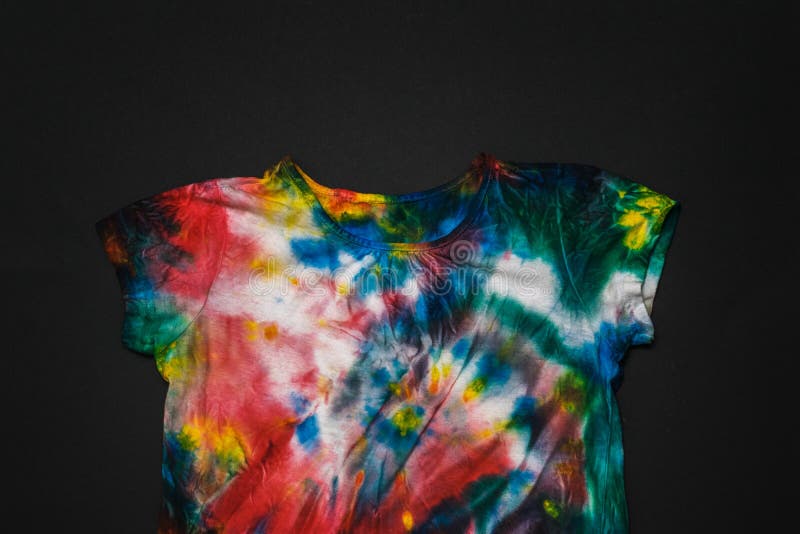 Multi-colored tie dye t-shirt on a black background. Flat lay.