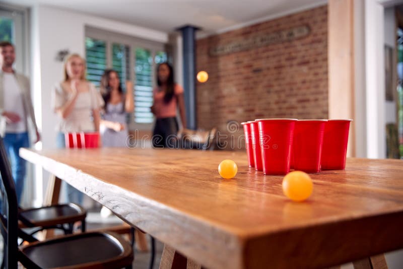 MultiCultural Group of Friends Playing Game at Home Together Throwing Ball into Plastic Cup