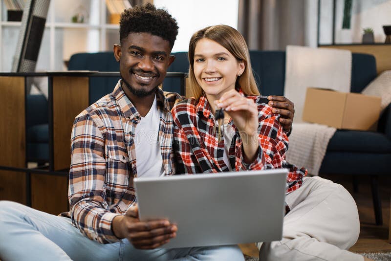 Multi ethnic family with keys and laptop sitting at new flat stock photos
