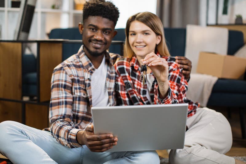 Multi ethnic family with keys and laptop sitting at new flat stock photos