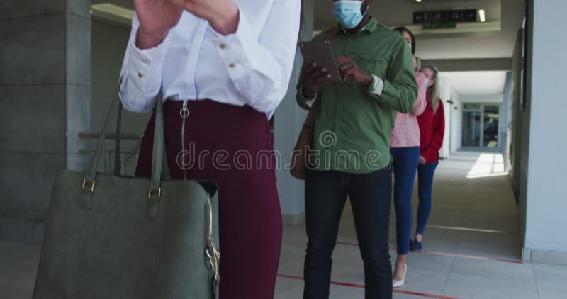 People wearing face masks using smartphones while standing in queue