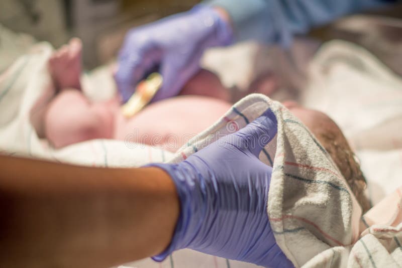 Multi-ethnic newborn baby immediately after being born / childbirth being cared for by nurses and health professionals