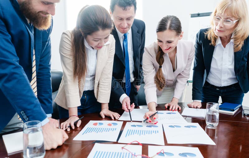 Multi-ethnic team of business people analyzing charts with statistics stock photos
