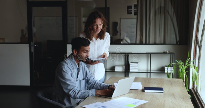 Multi-etnische collega's die het hebben over samenwerkingstaak op de werkplek