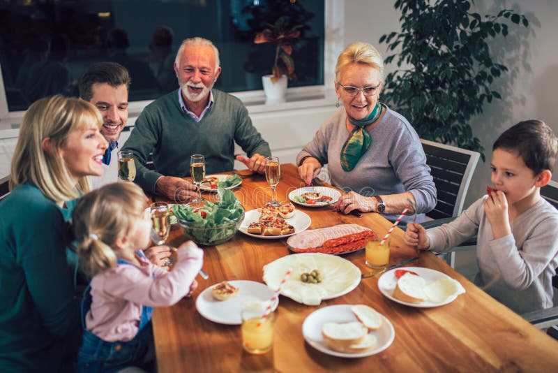 Multi generation family enjoying meal around table stock photography