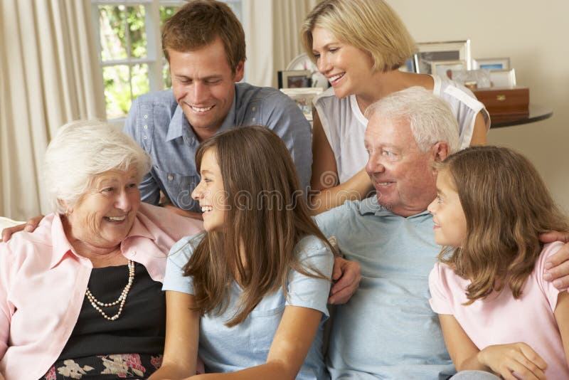 Multi Generation Family Group Sitting On Sofa Indoors