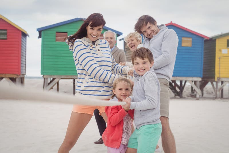 Multi-generation family playing tug-of-war at beach. Multi-generation family playing tug-of-war at beach